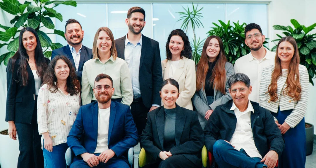 GoBuyBeauty team members posing together in a bright office surrounded by green plants.