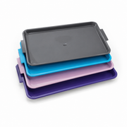 Set of four colorful RUCK® Large Instrument Trays stacked on a white background
